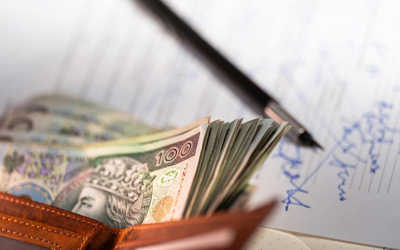 Japanese yen banknotes in a leather wallet beside handwritten financial paperwork and a pen.