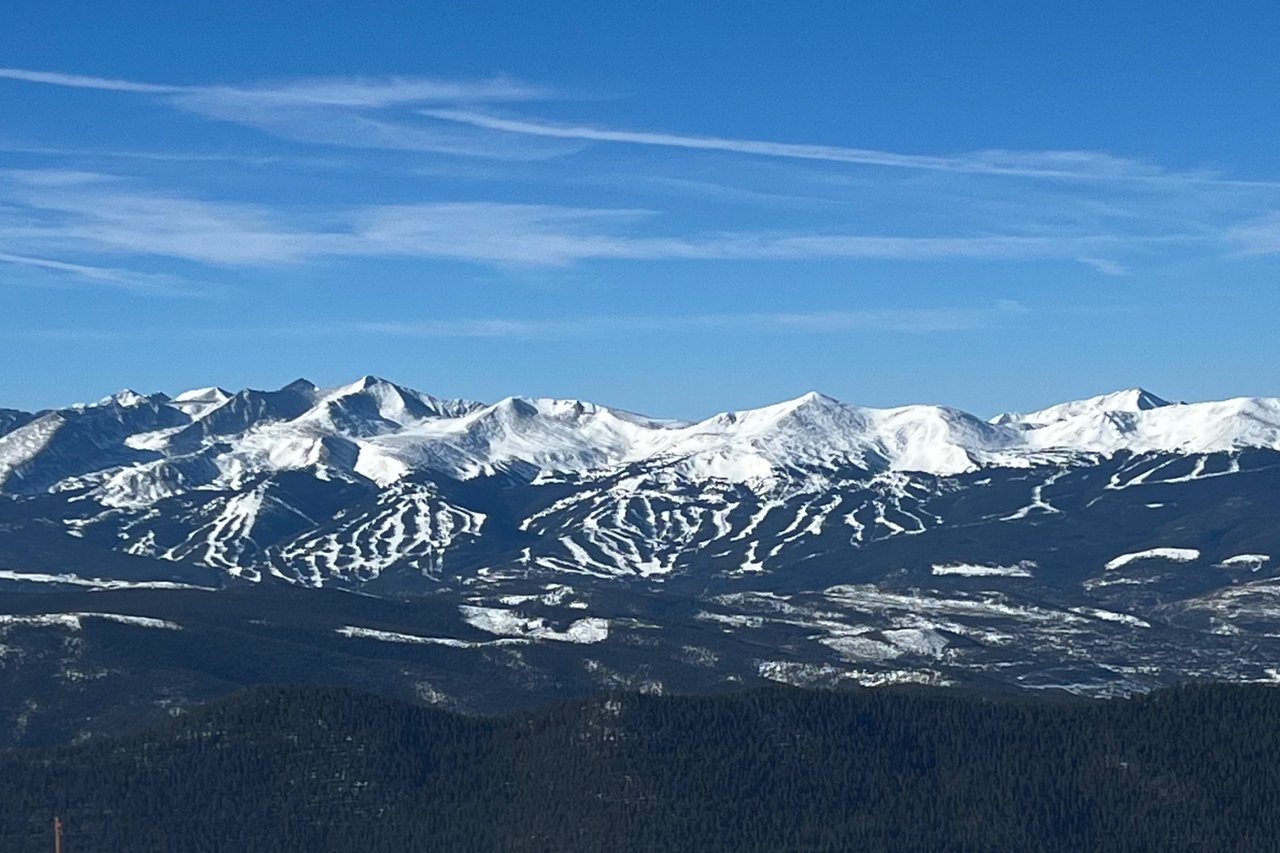 Snow-covered peaks and winding ski runs rise above dark forested slopes near Breckenridge.