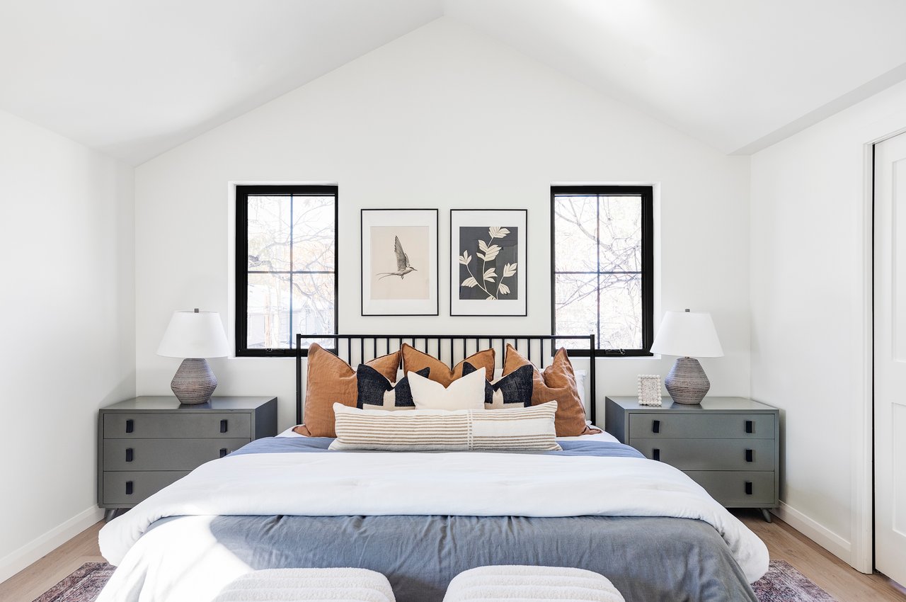 Primary suite with matching bedside tables, leather accent pillows and two windows