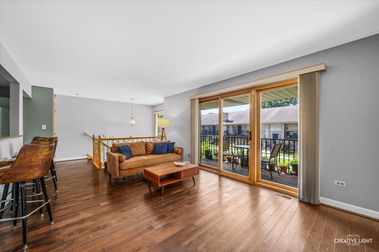 Hardwood floor living room with south facing balcony doors at 8316 Woodland Drive Darien IL