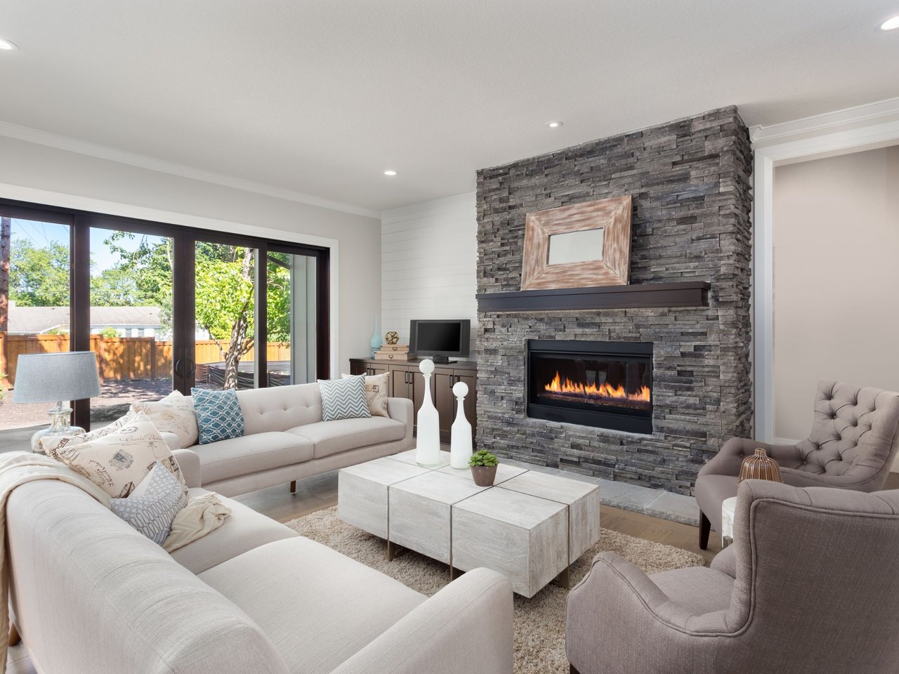 Bright living room with neutral seating, large sliding glass doors, and a floor-to-ceiling stone fireplace.
