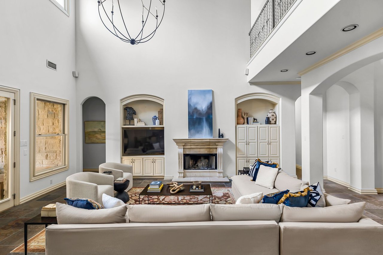 Great room with vaulted ceiling, stone fireplace, and built-ins at 5902 Saratoga Cove, Davenport Ranch, Austin, Texas.