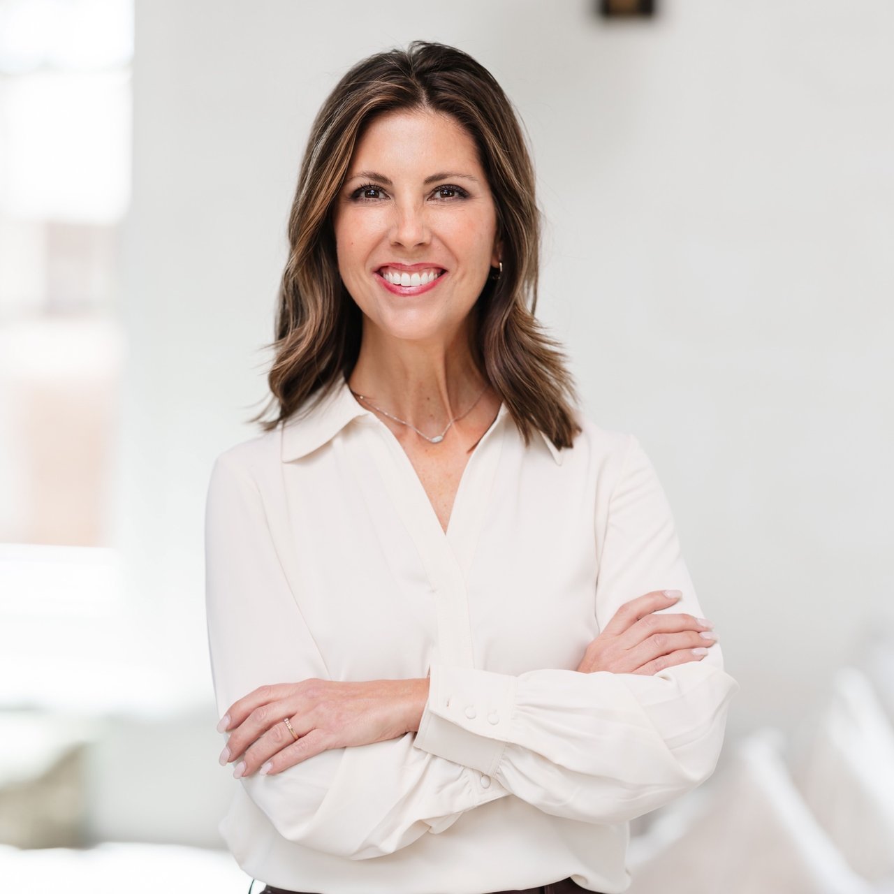 Shellie Hollingsworth smiling with her arms crossed in a white blouse.