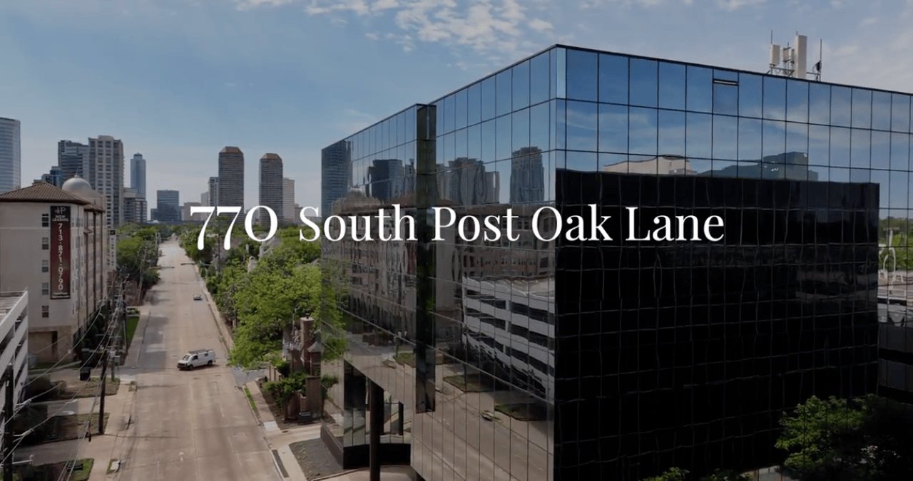 Glass office building at 770 South Post Oak Lane, with the Houston skyline and tree-lined street.