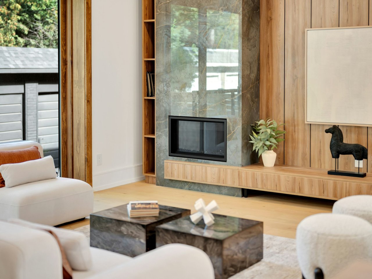 Living room with a stone fireplace wall, light wood cabinetry, and white seating.