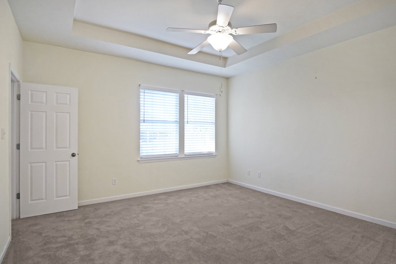 Bedroom at 5441 Hampton Hill Circle, Tallahassee, Florida 32311 with neutral walls, carpet flooring, ceiling fan, and tray ceiling detail.