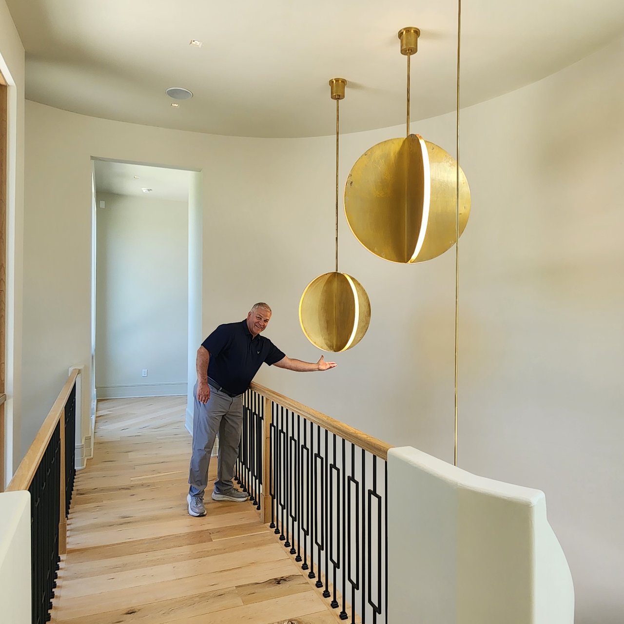 David Ludwig at an invitation-only broker tour inside a $4.75 million Powell Ohio luxury home, standing beside a sculptural gold pendant fixture on the upper landing