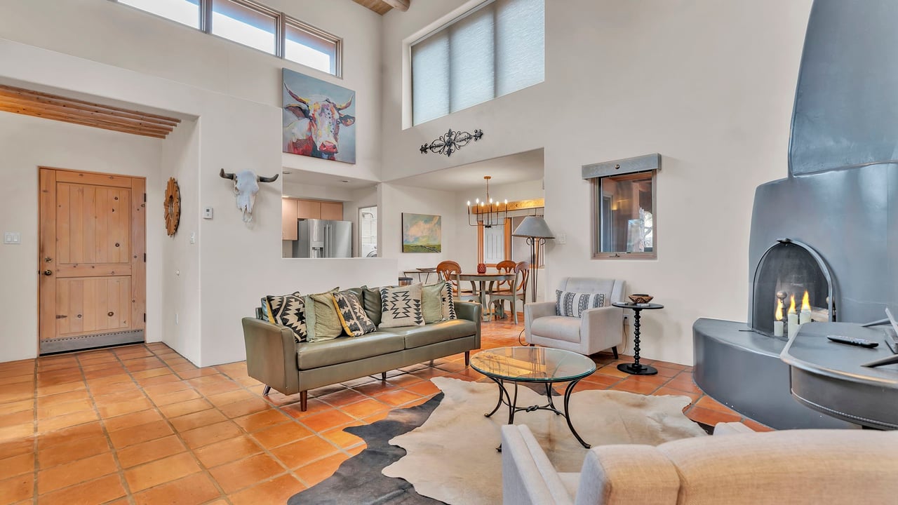 Living room with terracotta tile floors, high windows, and a large sculptural fireplace.