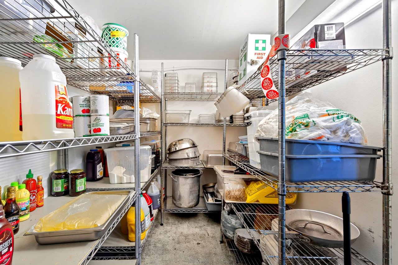 Restaurant pantry with wire shelving stocked with food supplies and cookware.
