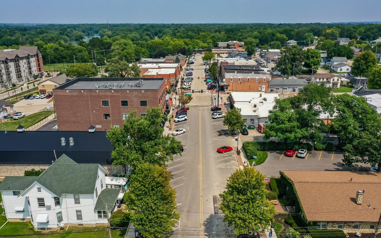Aerial view of a small town center with a tree-lined main street and brick commercial buildings.