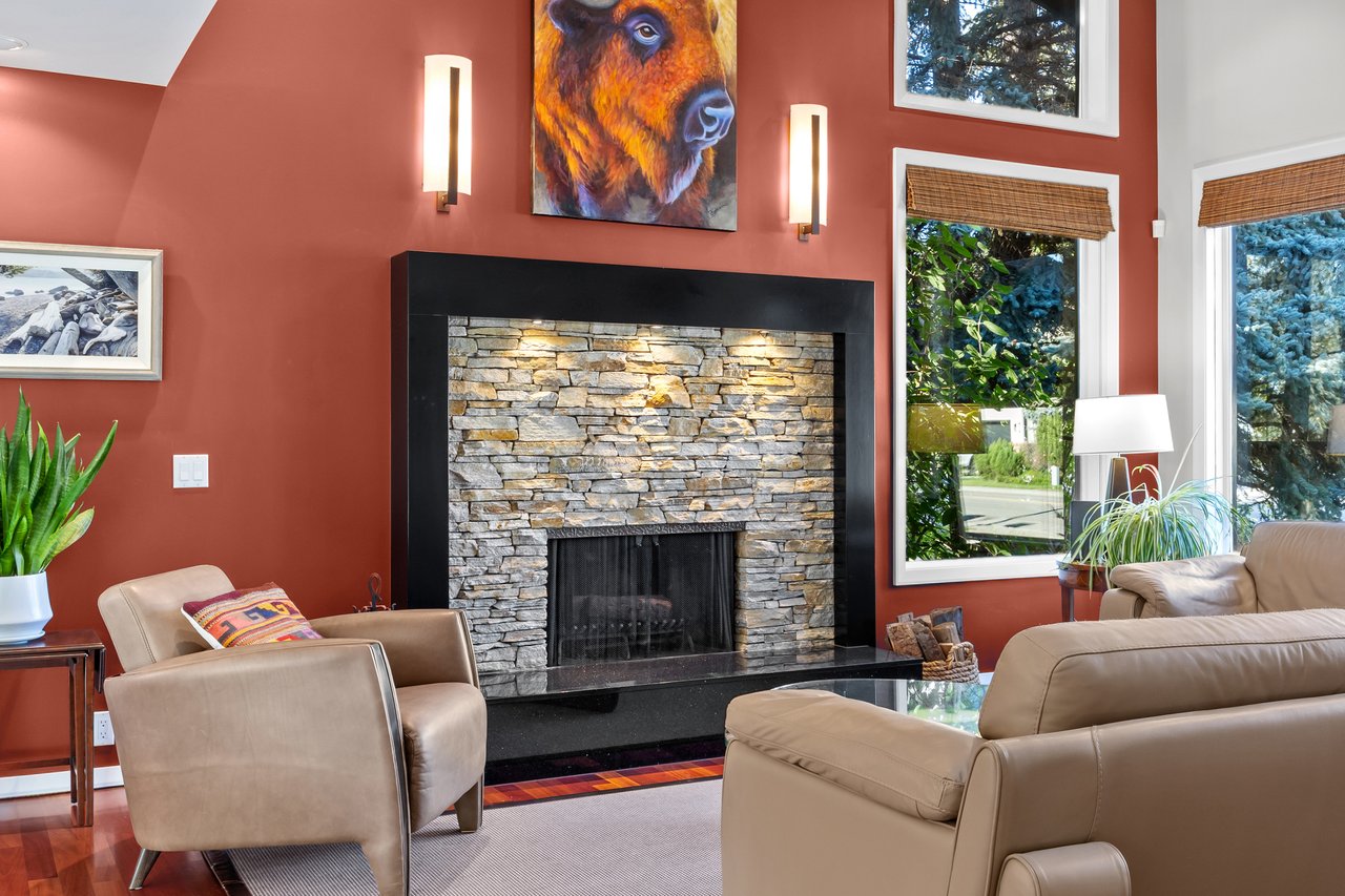 Living room with a stone fireplace, leather seating, and a buffalo painting above the mantel.