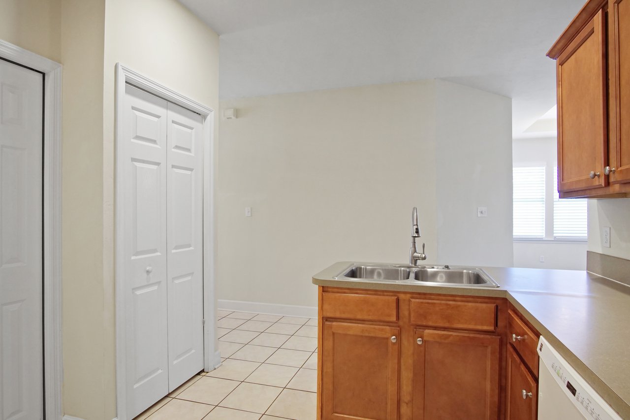 Kitchen view at 5441 Hampton Hill Circle, Tallahassee, Florida 32311 showing double sink island, tile flooring, and nearby pantry doors.