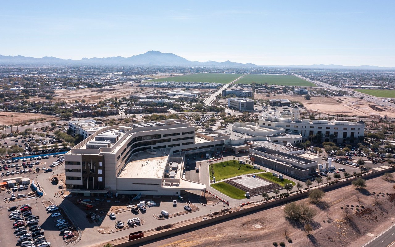 Aerial view of modern buildings, surrounding development, and mountains on the horizon.