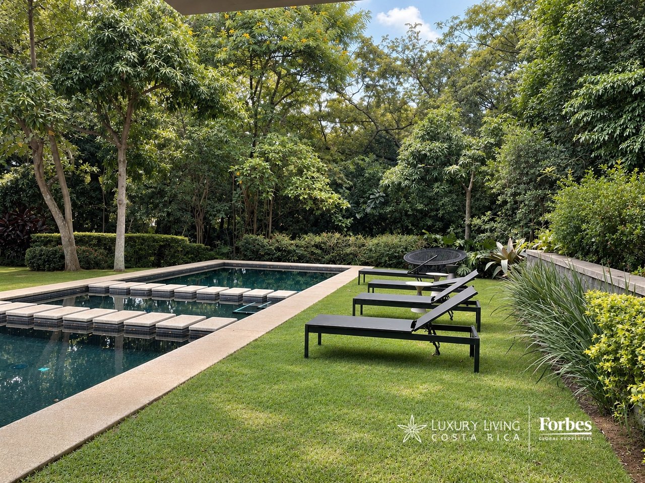 Garden pool with stepping stones, black lounge chairs, and dense tropical landscaping.