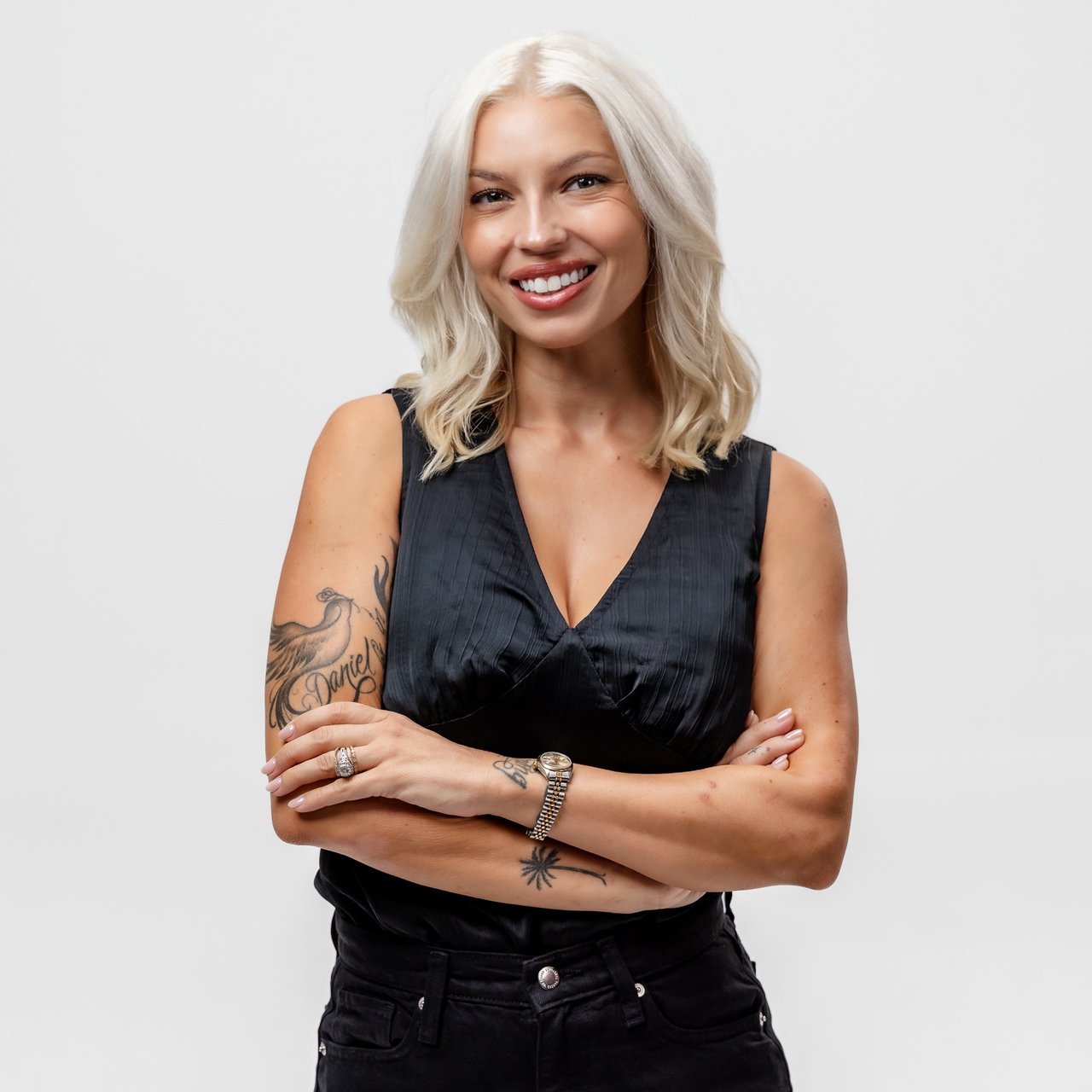 Payton McCornack smiling with her arms crossed, wearing black and showing tattoos on her arms.