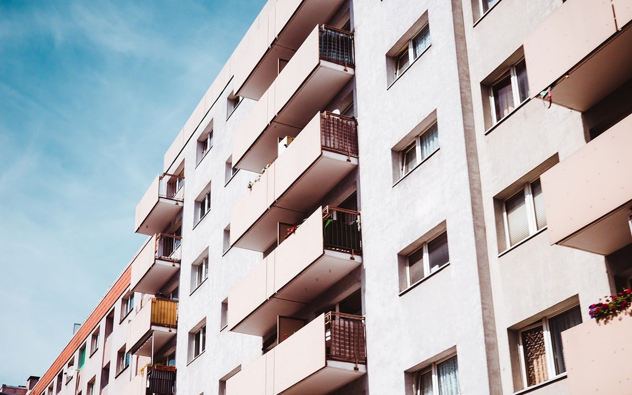 Modern white condominium building with projecting balconies and rows of windows.