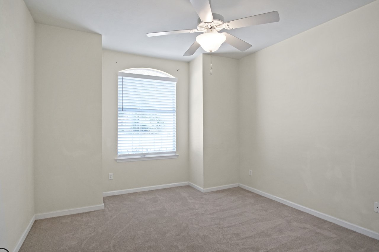 Bedroom at 5441 Hampton Hill Circle, Tallahassee, Florida 32311 featuring arched window, neutral carpet, and ceiling fan.