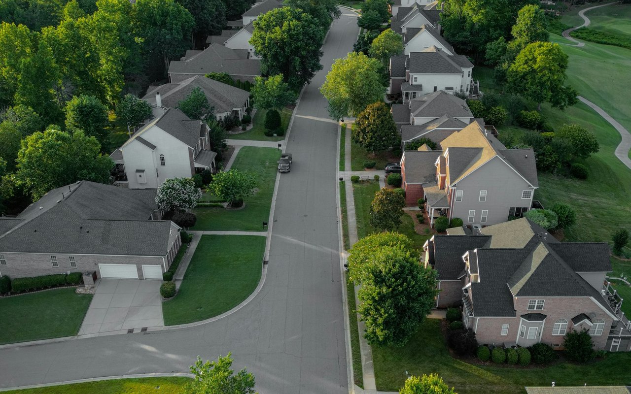 Aerial view of homes along a tree-lined residential street.
