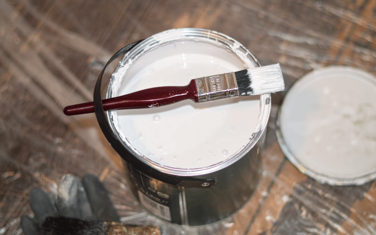  A partially full can of white paint with a metal handle is seen from above.