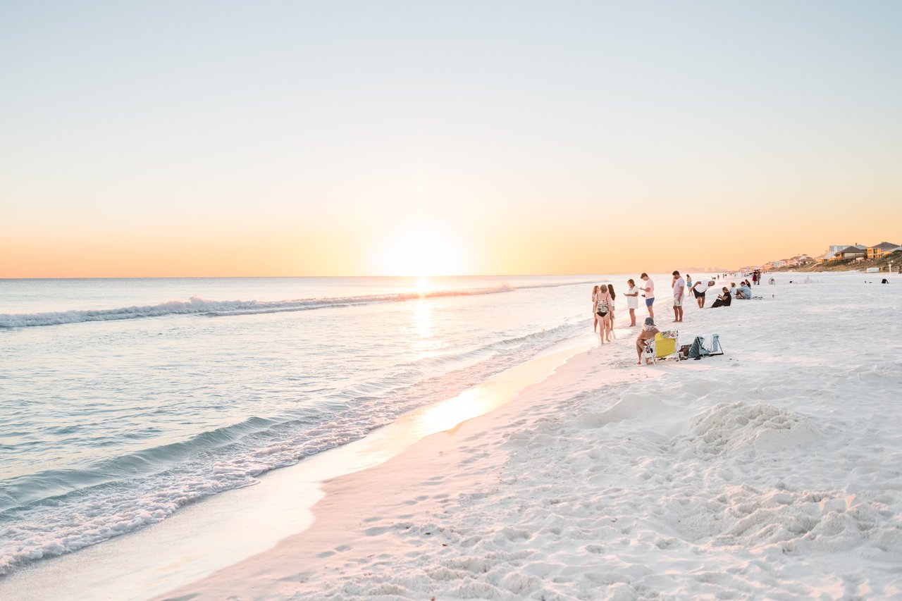 Golden sunset over the Gulf of Mexico with beachgoers along sugar-white sand at Watersound Beach on 30A, Florida