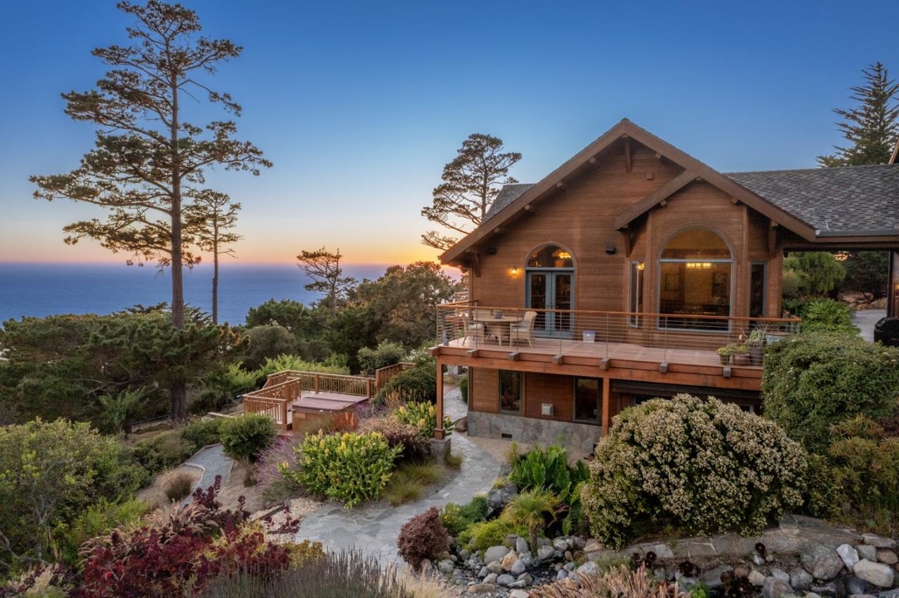 Twilight exterior of $5.5M Carmel Highlands timber home with ocean views and landscaped surroundings