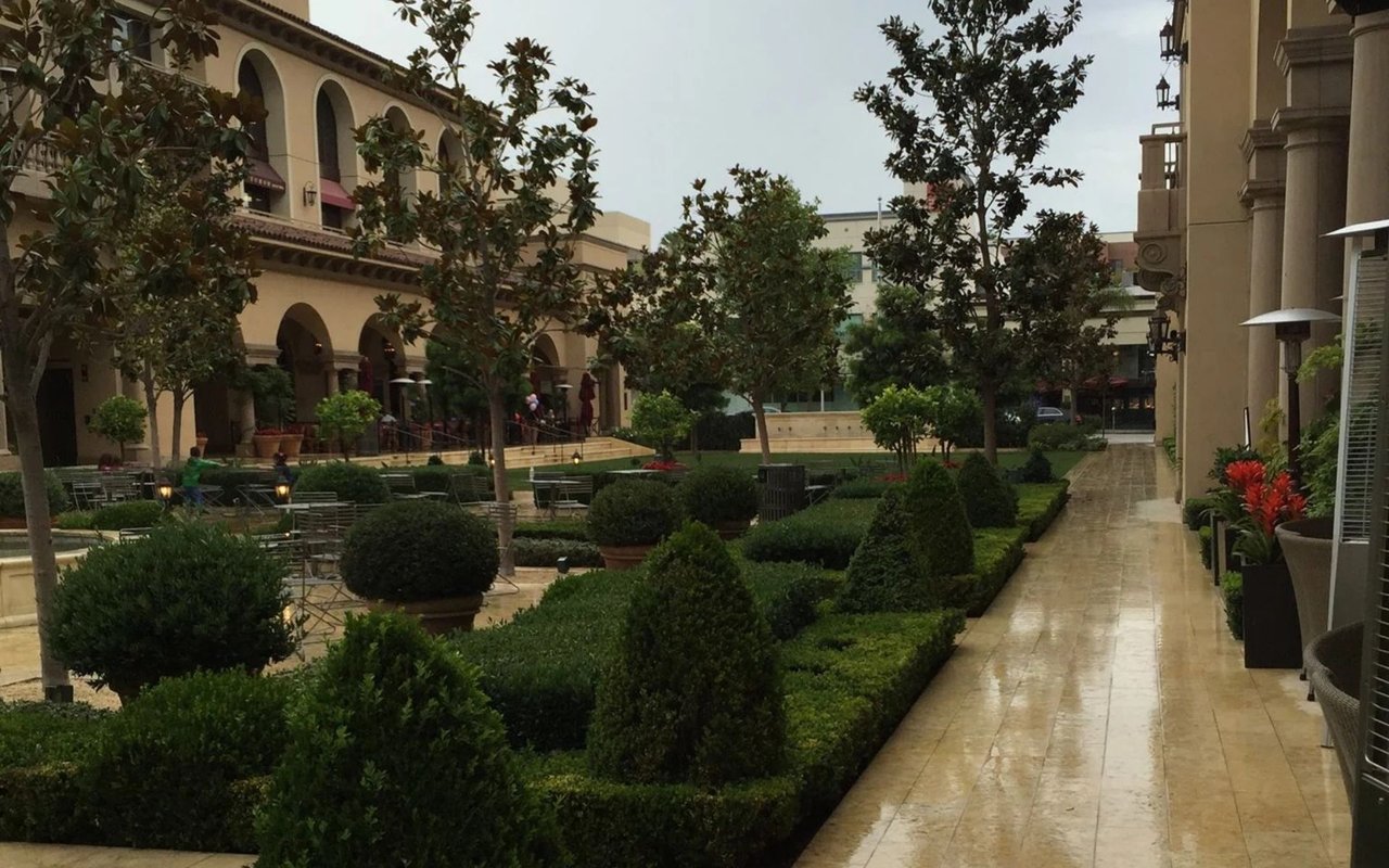 Montage Beverly Hills courtyard with manicured hedges, outdoor seating, and a stone walkway.