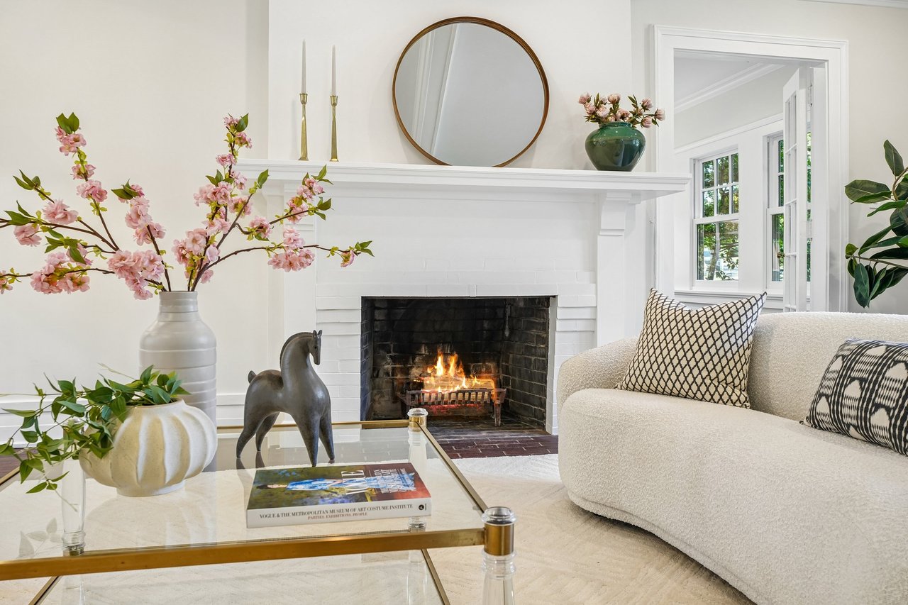 Living room with a white brick fireplace, lit fire, cream sofa, and glass coffee table.