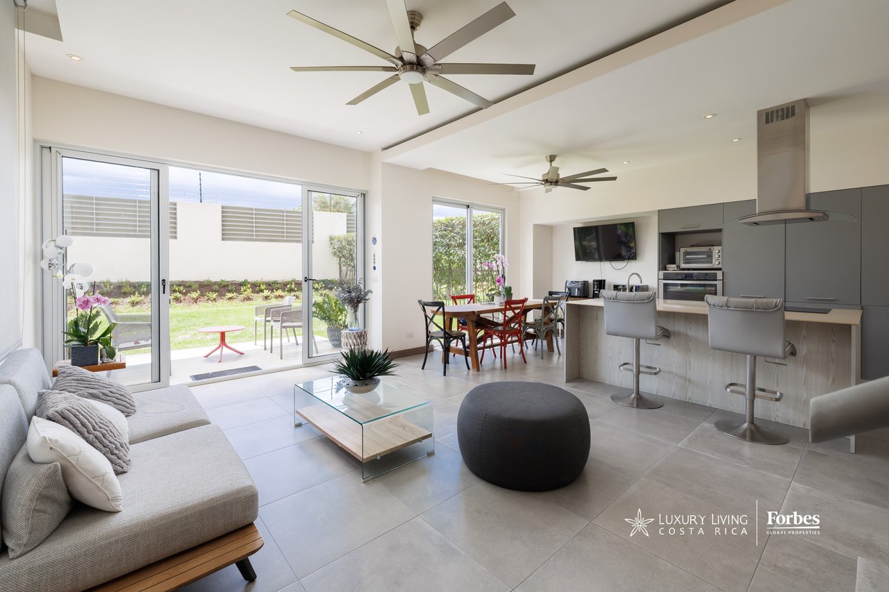 Open-plan living room with kitchen island and dining area, opening onto a private garden.