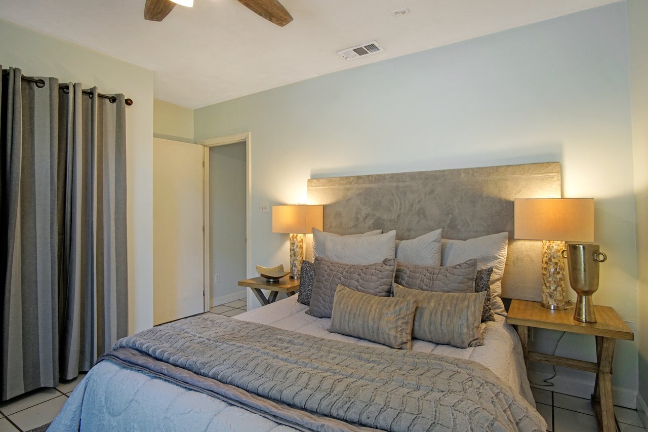 Cozy bedroom with soft lighting features a bed with a textured gray headboard, neutral pillows and blankets, flanked by wooden side tables with lamps.Cozy bedroom with soft lighting features a bed with a textured gray headboard, neutral pillows and blankets, flanked by wooden side tables with lamps.