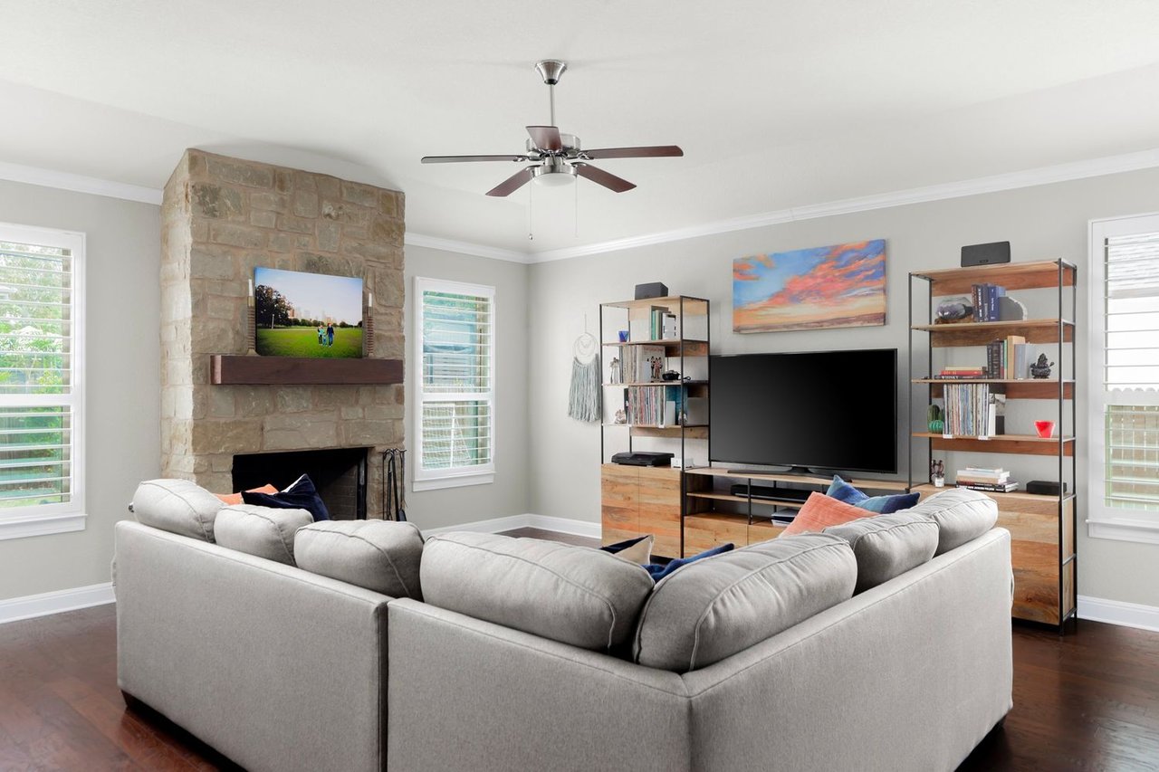 Living room with a gray sectional, stone fireplace, and wood entertainment unit.