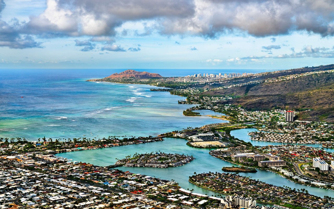 Aerial view of Hawaii Kai’s marina and coastal neighborhoods beside turquoise water and green hills.