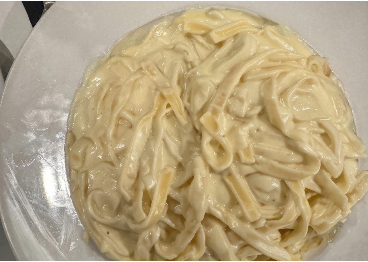 Creamy ribbon pasta piled on a white plate.