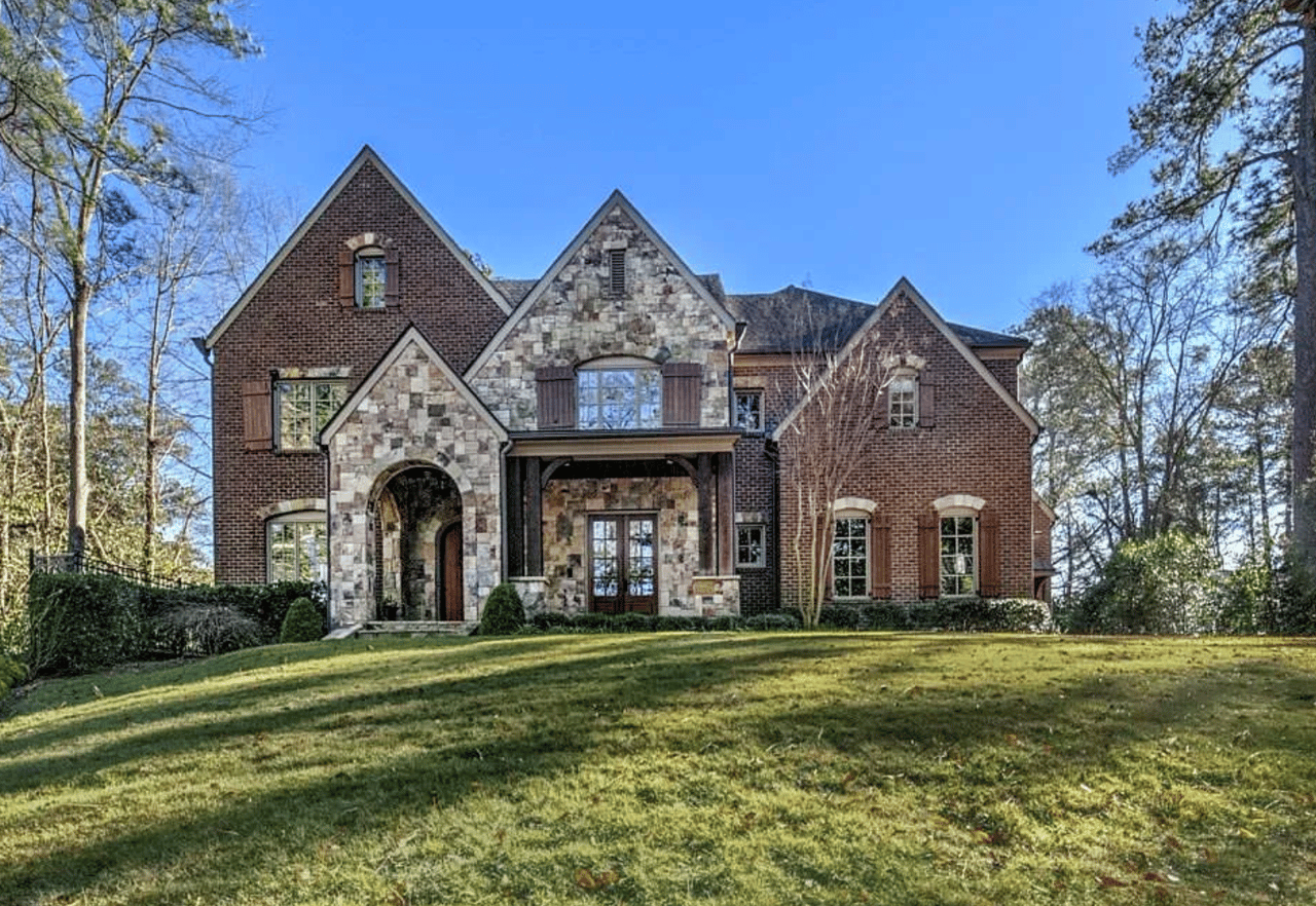 Two-story brick and stone home with multiple gables and an arched front entrance.