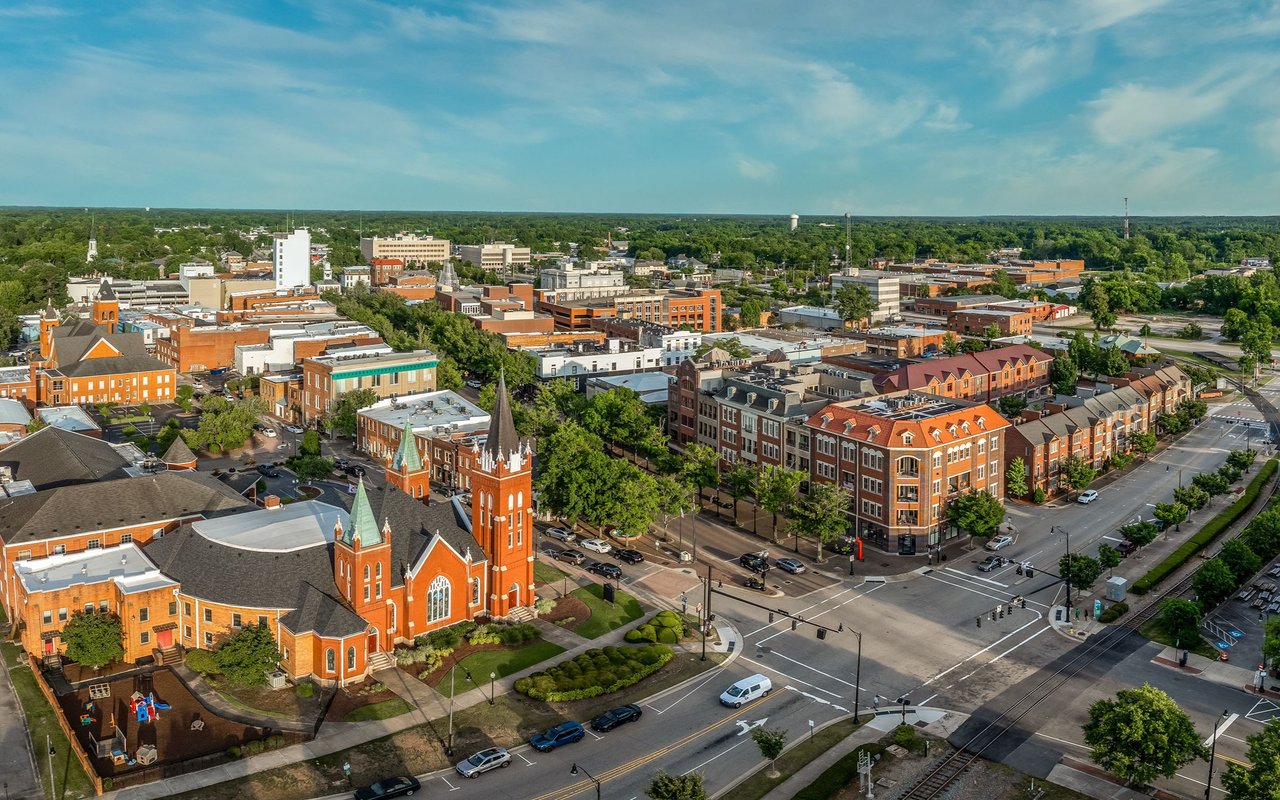 Aerial view of a town center, with a red-brick church beside downtown streets and buildings.