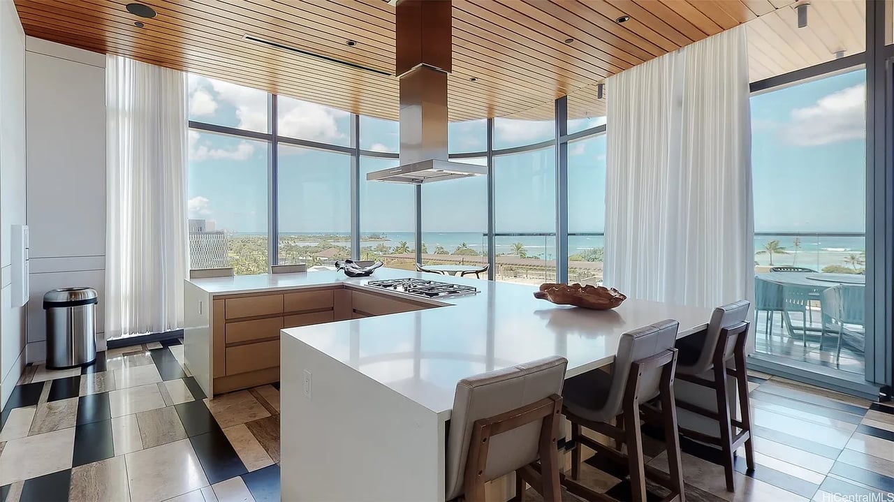 Modern kitchen with a large island and floor-to-ceiling windows overlooking the ocean.