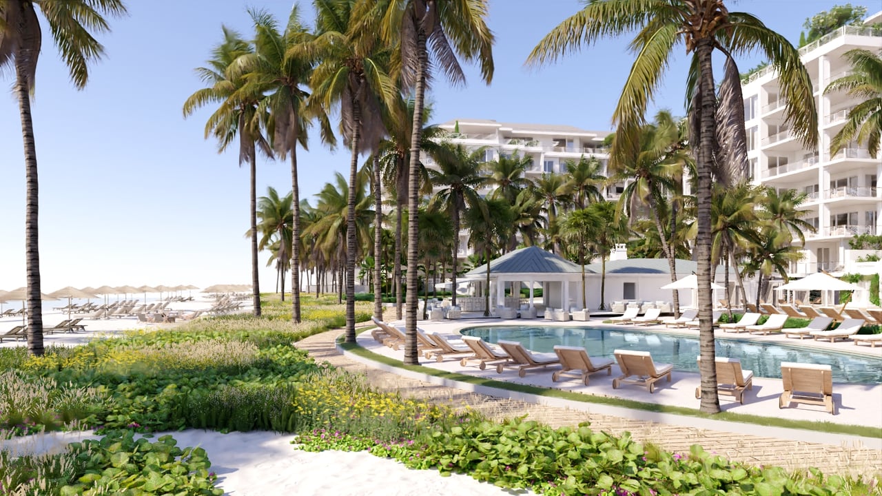 Coastal resort with a palm-lined pool, white buildings, and a beach with umbrellas.