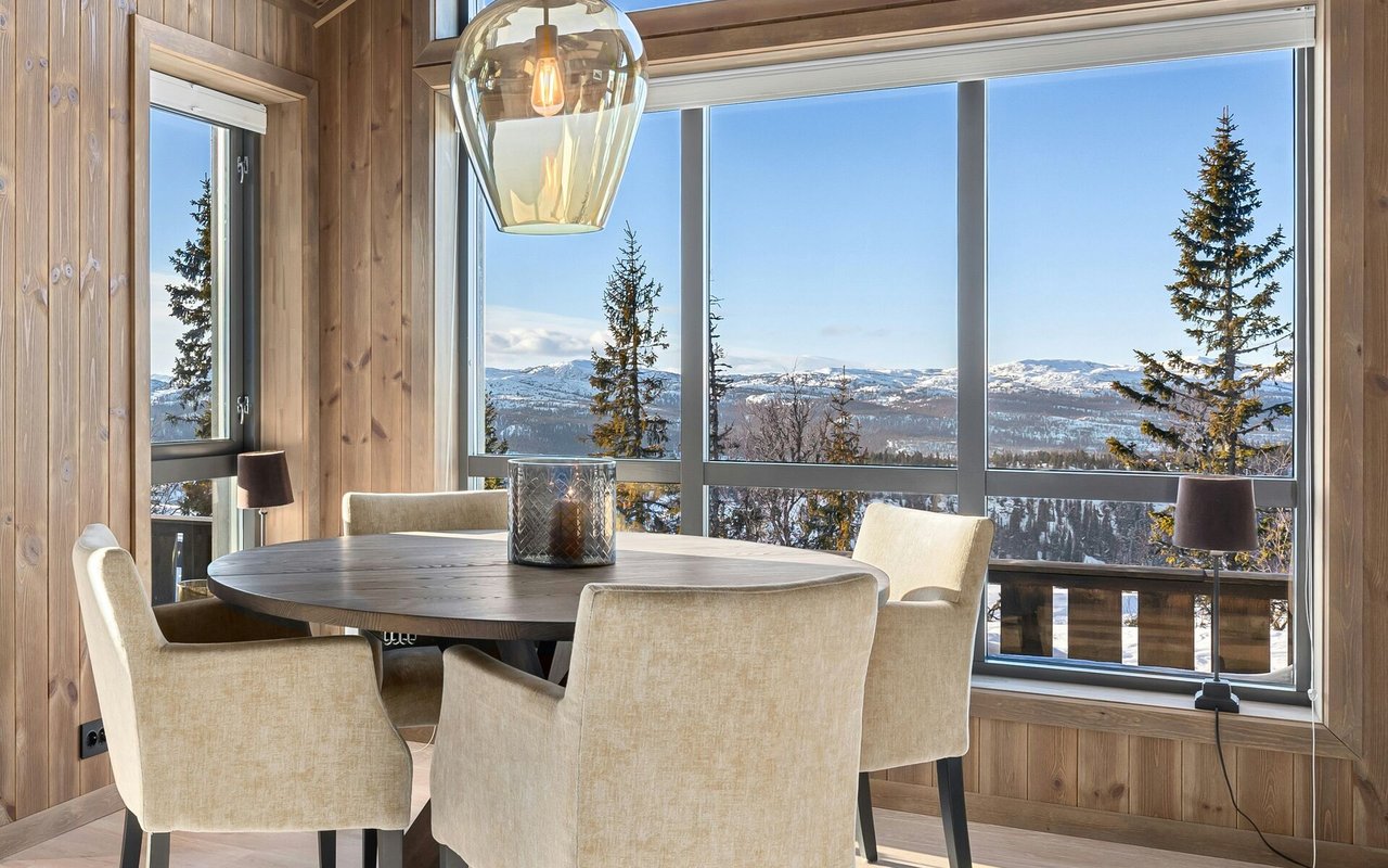 Dining area with expansive windows overlooking snowy mountains.