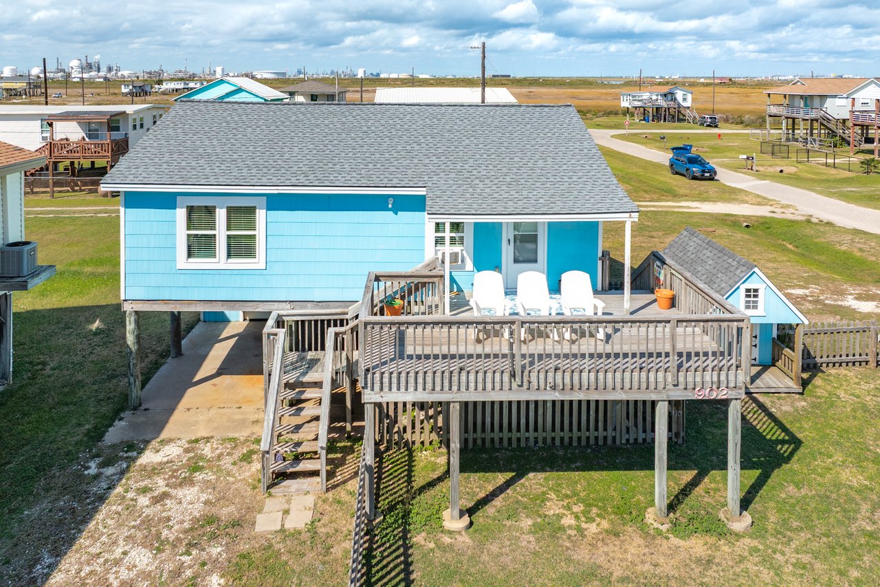 Exterior of 902 Treaty Dr, Surfside Beach TX — a blue coastal cottage with covered deck and spacious double corner lot just blocks from the beach