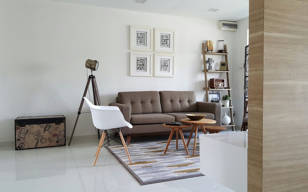 Living room with a taupe sofa, white accent chair, and ladder-style display shelf.