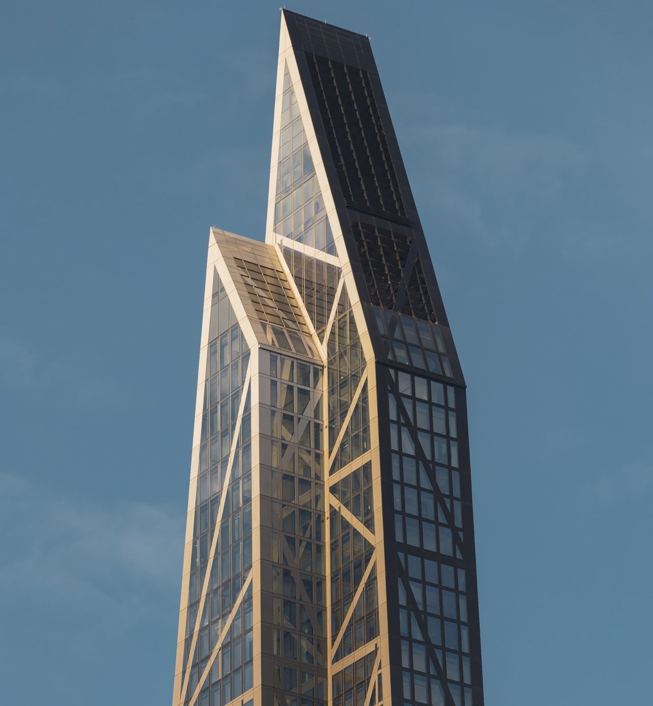 53 West 53 skyscraper with angular crown and diagonal braces against a blue sky.