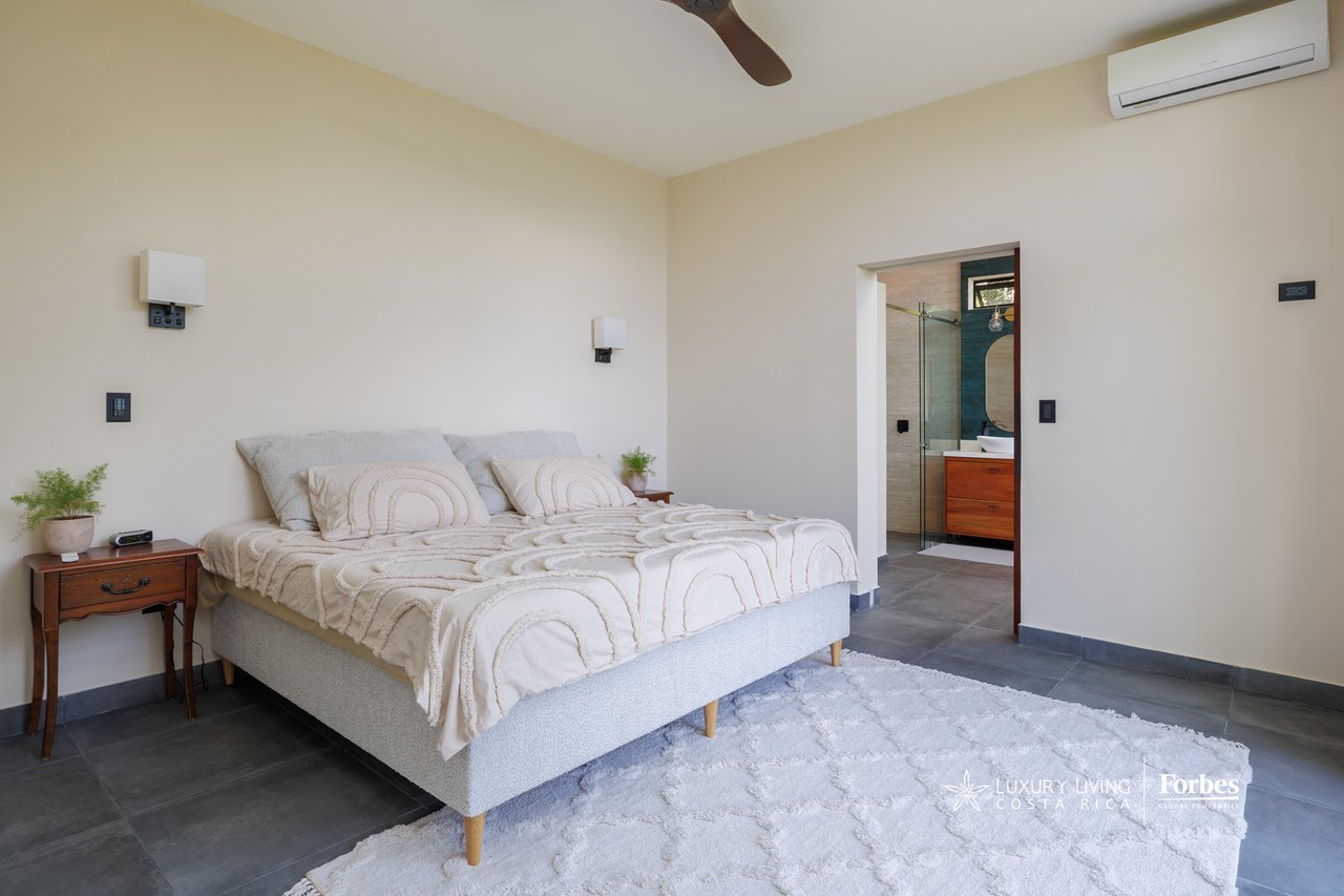 Furnished bedroom with a large bed and an open doorway to the ensuite bathroom.