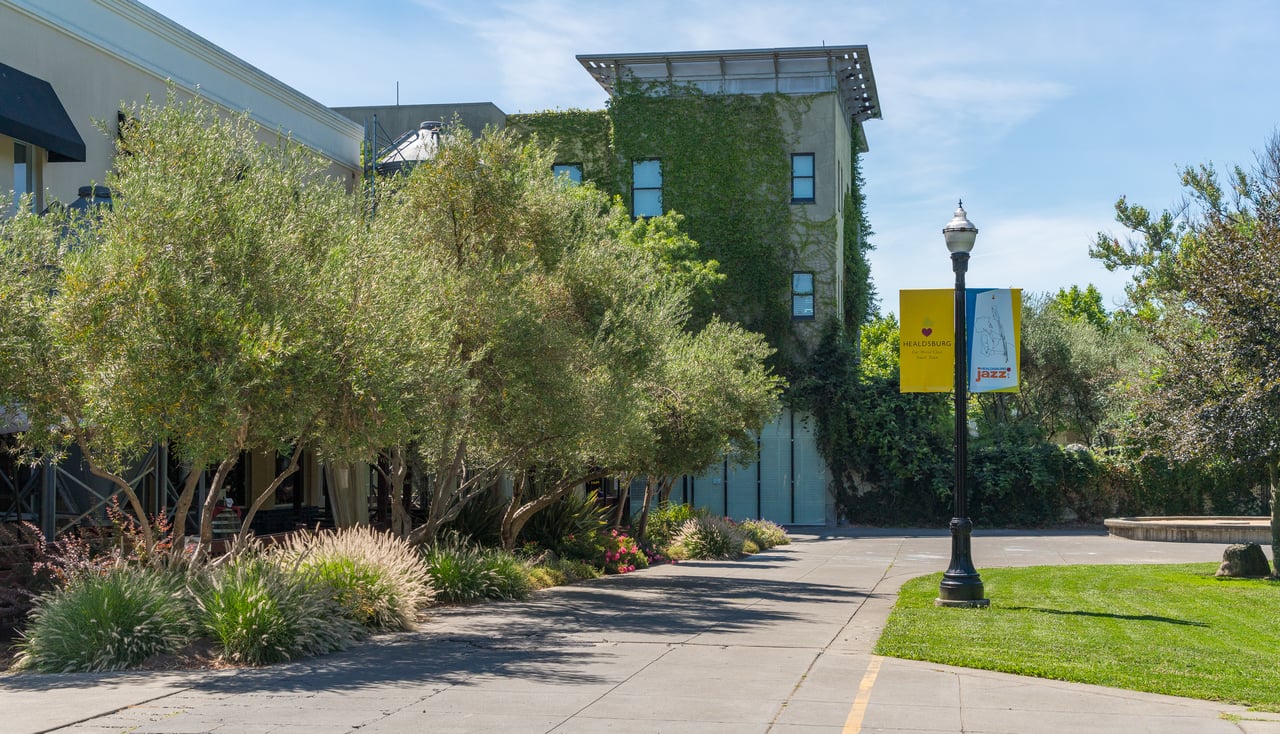 Modern ivy-covered building beside a landscaped Healdsburg plaza with event banners.
