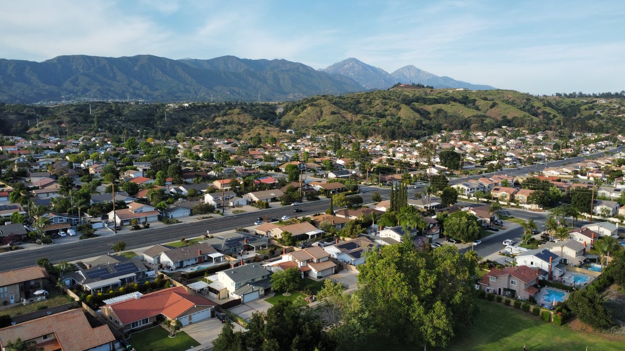 Aerial view of Duarte homes and streets beneath green foothills and mountains.