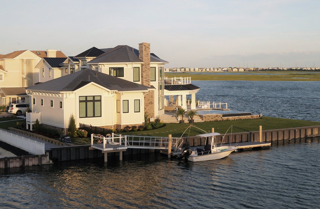 Waterfront home with a stone chimney, private dock, and motorboat moored beside it.