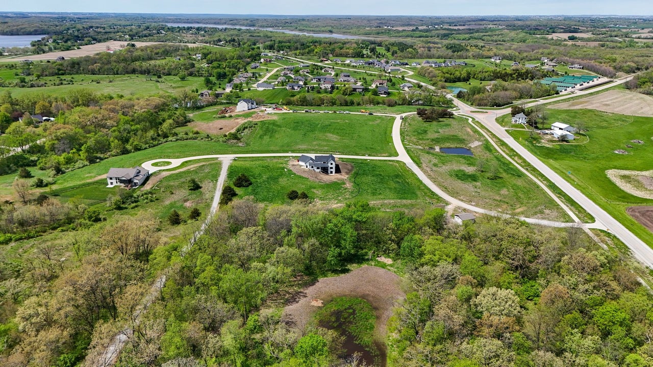 Aerial view of Oak Meadow, with winding roads, green lots, scattered homes, and wooded surroundings.