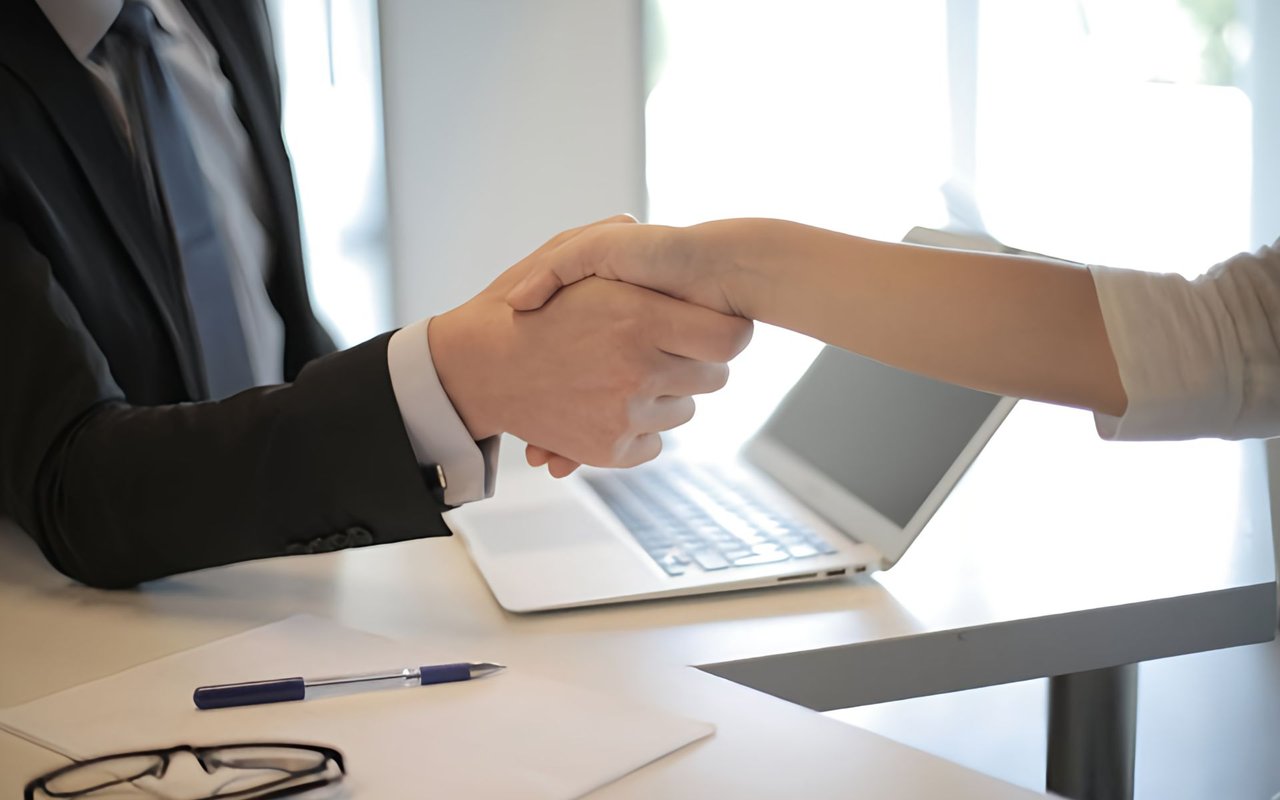  Close-up shot of two people shaking hands over a white table