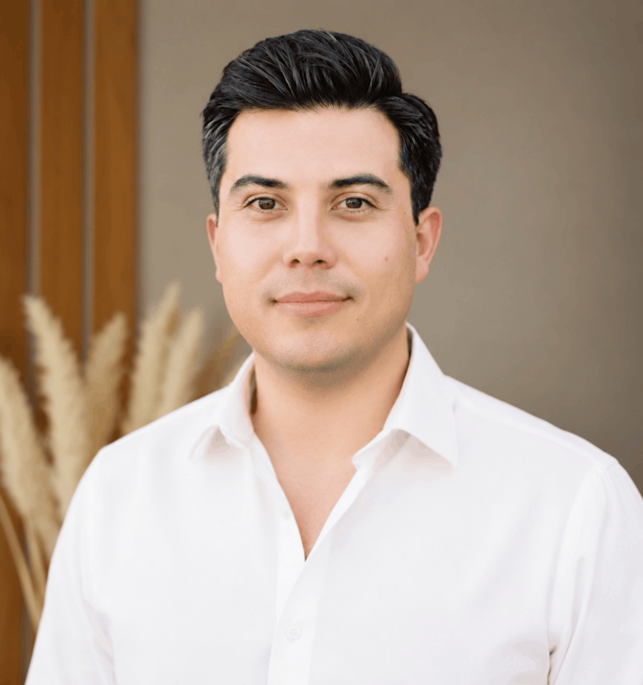 Brandon Valle in a white collared shirt against a warm neutral background.