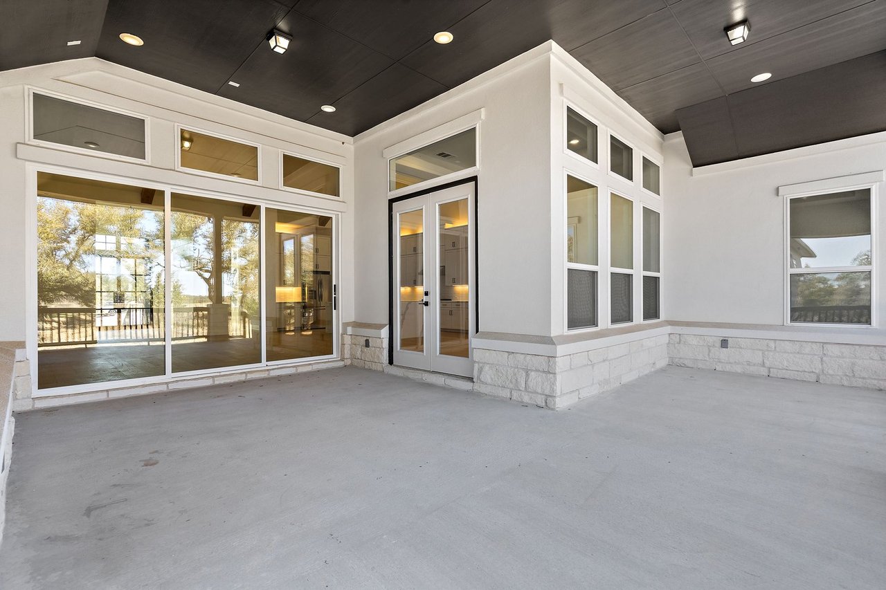 Flex space with floor-to-ceiling windows opening toward a covered patio at 133 Mataro Cove in the Cortaro neighborhood of Dripping Springs, Texas.