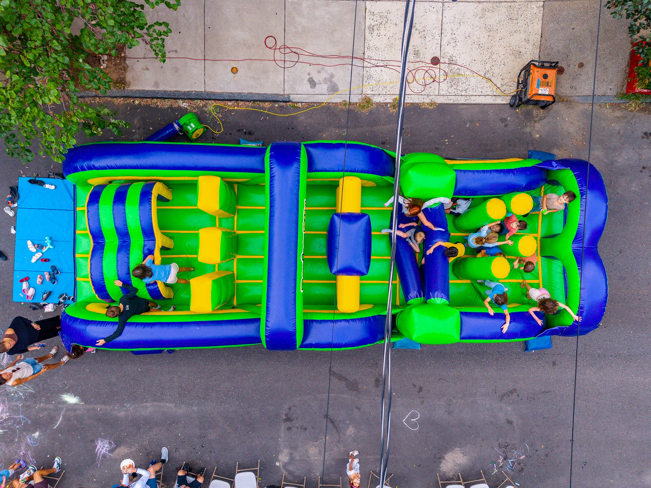 Children play on a colorful inflatable obstacle course at a neighborhood block party.
