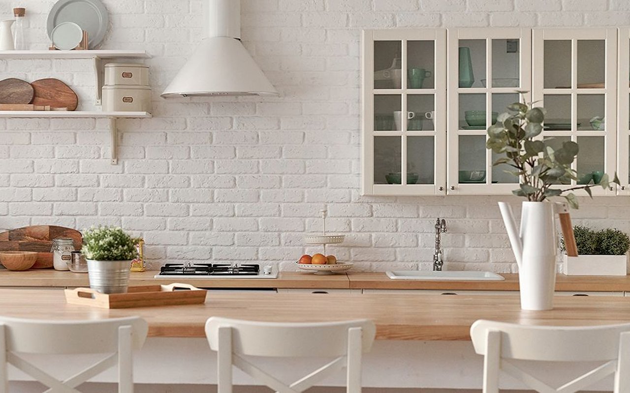 Staged kitchen with white brick backsplash, wood counters, glass-front cabinets, and breakfast seating.